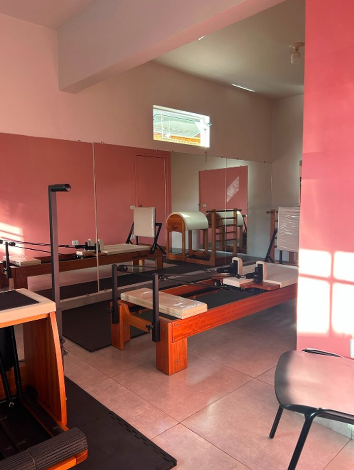 Estúdio de Pilates com aparelhos reformer de madeira e paredes em tom terracota